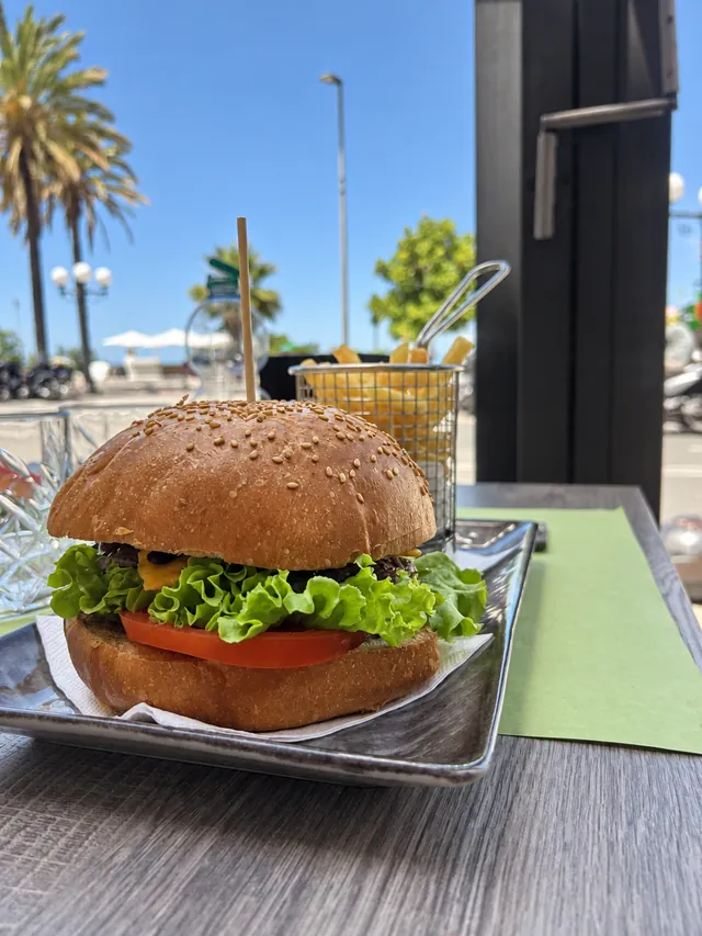 Hamburger con insalata, pomodoro e formaggio, con patatine, di giorno vicino al mare