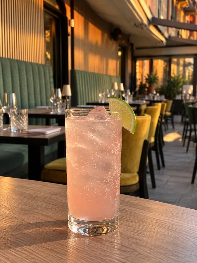 Un cocktail rosa con ghiaccio e lime sul tavolo della veranda