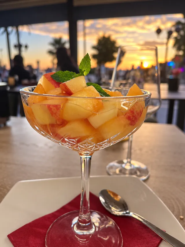 Coppa di frutta fresca a cubetti con menta, al tramonto sulla veranda