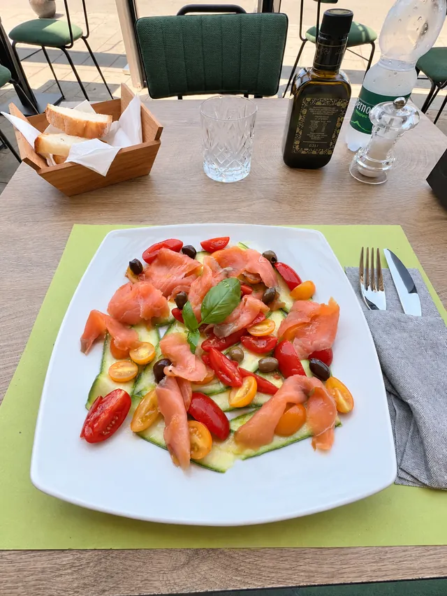 Piatto di salmone con pomodorini, olive e basilico